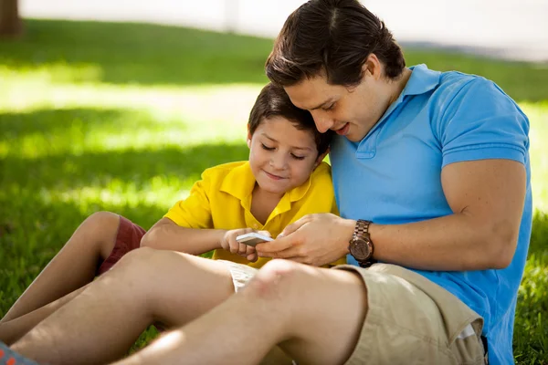 Отец и его сын пользуются телефоном на открытом воздухе — стоковое фото