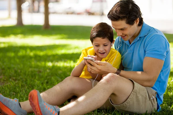 Far och hans son med telefonen utomhus — Stockfoto