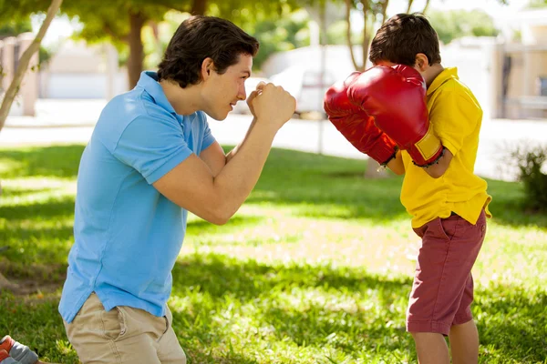 Отец и его сын боксируют в боксёрских перчатках. — стоковое фото