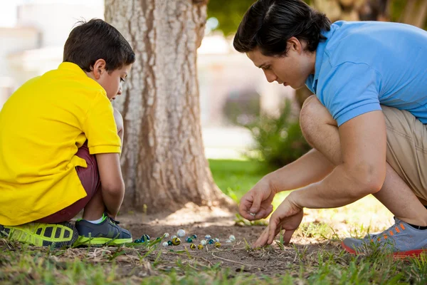 Papá jugando canicas con su hijo — Foto de Stock