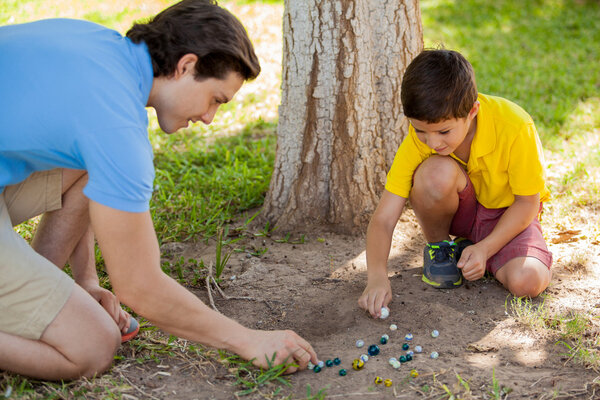 Boy playing marbles with his father