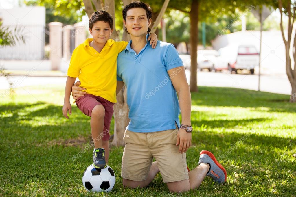 Father and his son with foot on soccer ball