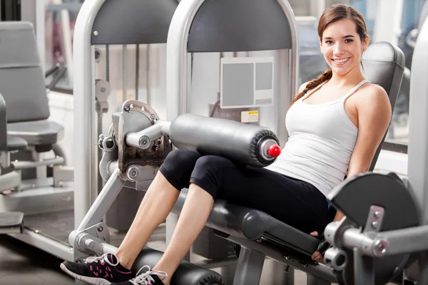 The girl shakes her legs on the simulator — Stock Photo, Image