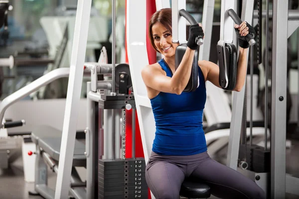 Girl shakes muscle simulator — Stock Photo, Image