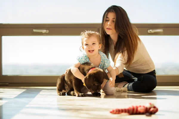 Moeder en dochter spelen met een hond — Stockfoto
