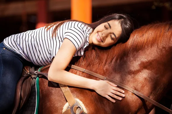 Brünette gibt ihrem Pferd eine Umarmung, während sie ihn reitet — Stockfoto