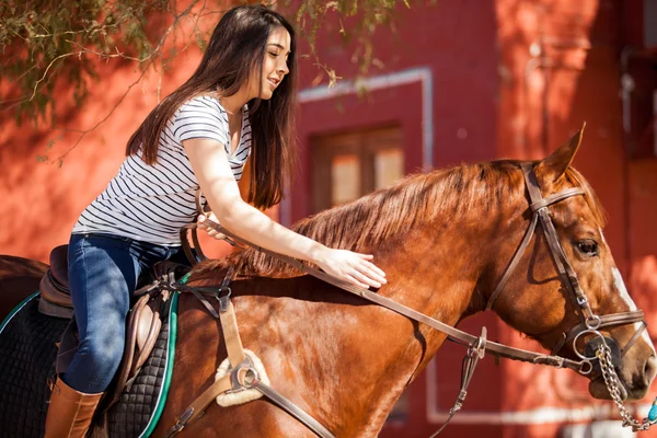 Bruna cavalcando un cavallo e accarezzandolo — Foto Stock