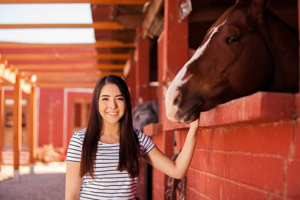 Vrouw die lacht naast haar paard op de stallen — Stockfoto