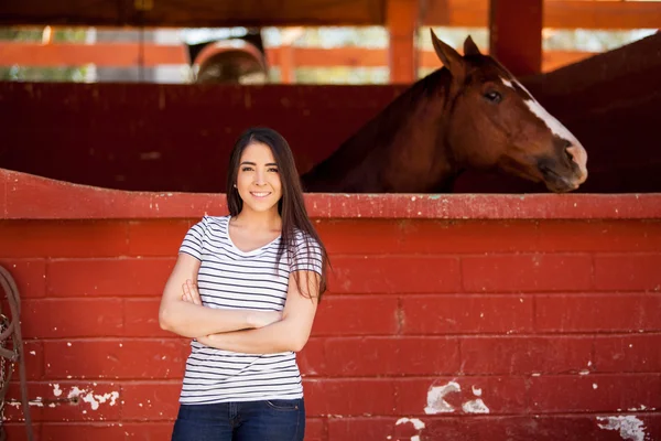 Donna in piedi accanto al suo cavallo in una stalla — Foto Stock