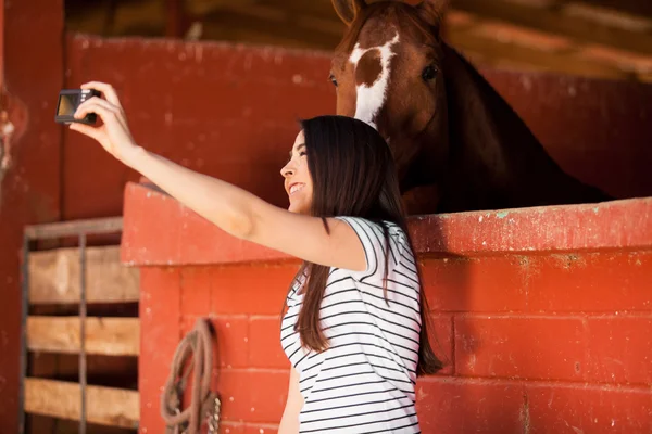 Mujer divirtiéndose y tomando una selfie con un caballo — Foto de Stock