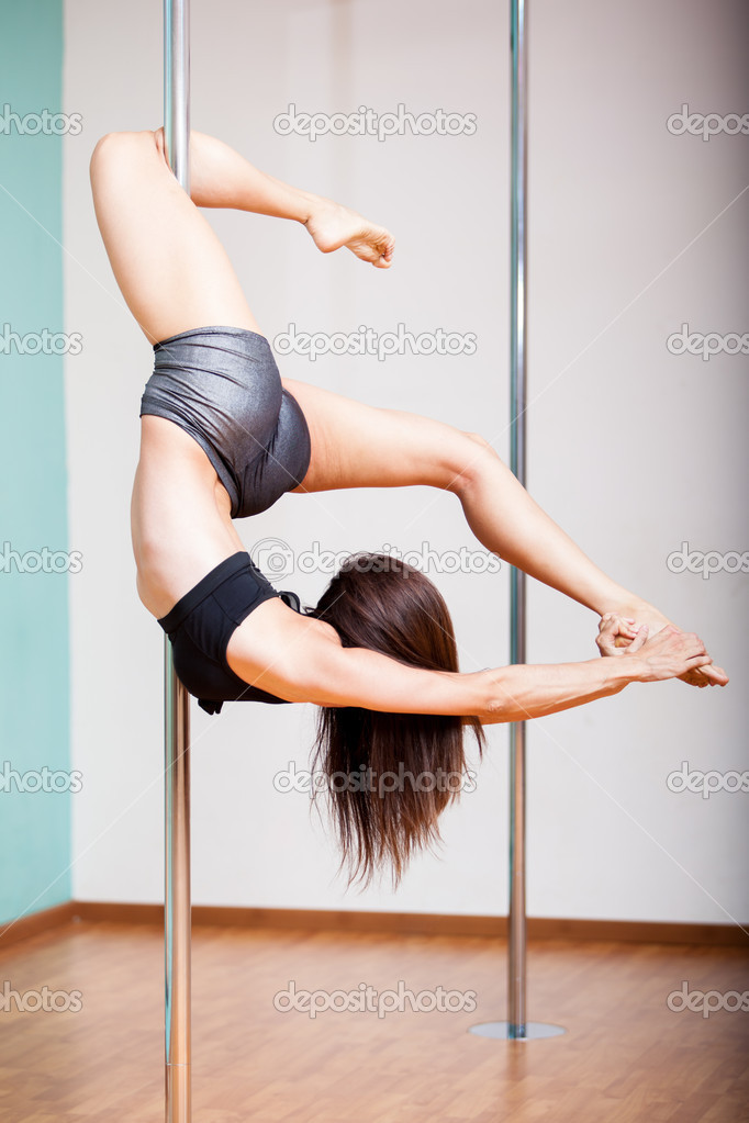 Pole fitness instructor practicing a difficult pose