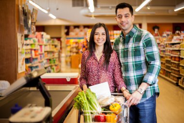 sevimli genç bir çift ayakta ürünleri kasada mağaza ile bir arabası ile