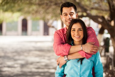 sevimli genç çifte sarılma ve parkta gülümseyen