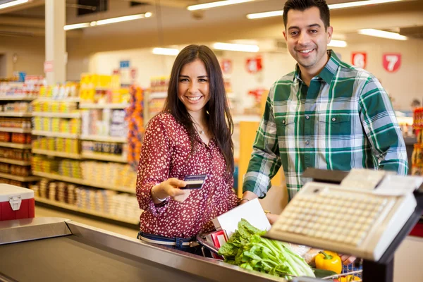 Linda pareja joven comprando comestibles con una tarjeta de crédito — Foto de Stock