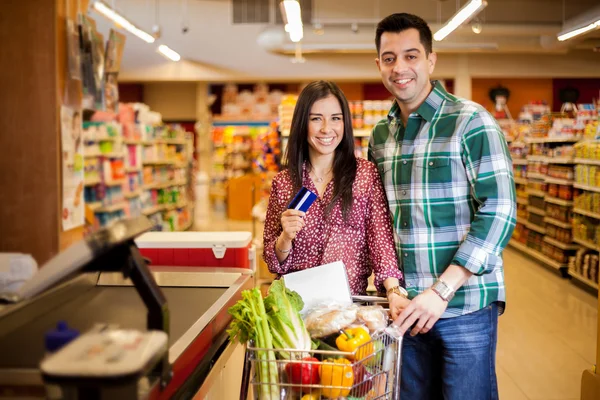 Linda pareja joven usando una tarjeta de crédito en la tienda — Foto de Stock