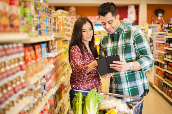 Gelukkige paar kijken naar het winkelen lijst in de winkel — Stockfoto