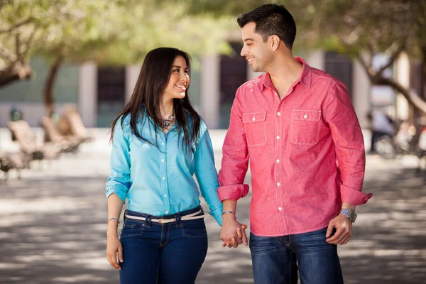 Милая молодая пара, держащаяся за руки и гуляющая вместе в парке — стоковое фото