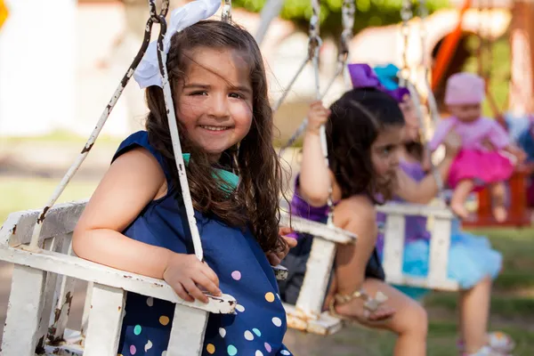 Group of cute little friends having fun on a park swing and smiling — Stock Photo, Image