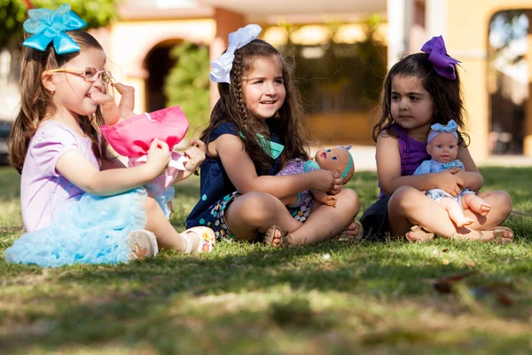 Lindas hermanitas hispanas jugando con sus muñecas en un parque —  Fotos de Stock