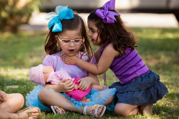 Bella bambina raccontando il suo amico un segreto mentre si aggira in un parco — Foto Stock