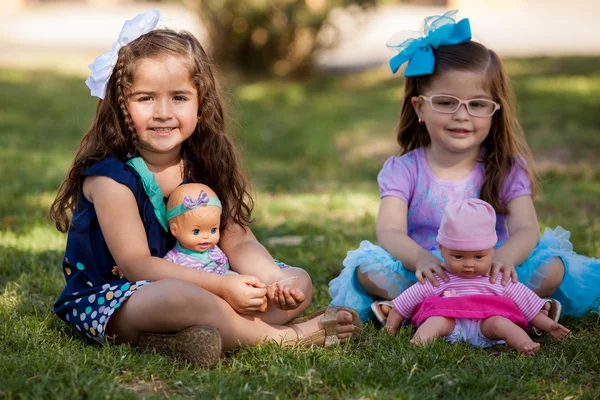 Ouple de meninas bonitas brincando com suas bonecas em um parque — Fotografia de Stock