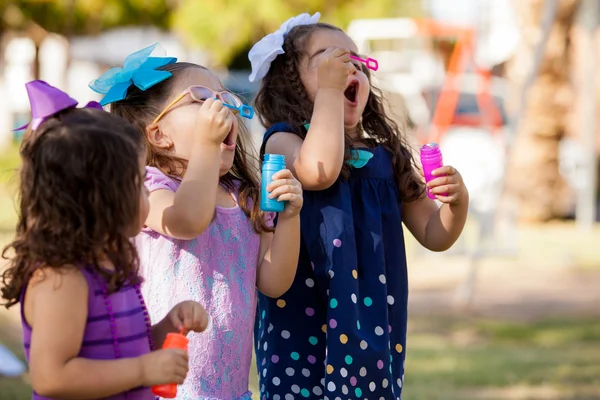 Маленькие девочки пытаются сделать больше пузырей, чем их друзья — стоковое фото