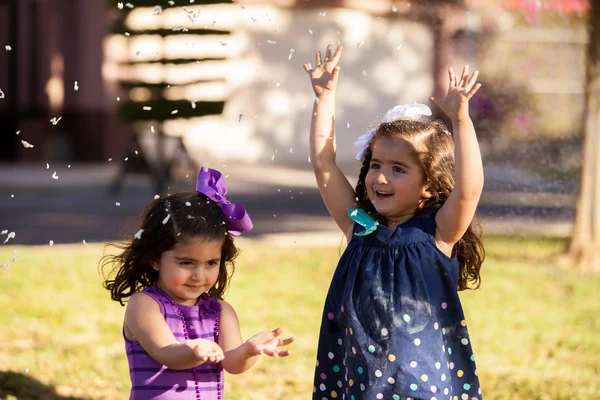 Little sisters having fun with some foam that looks like snow at a park — Stock Photo, Image