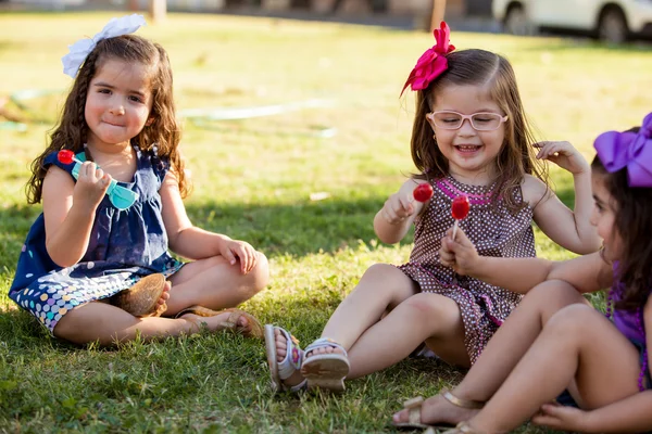 Cute Latin little friends eating some lollipops together on a day of summer — Stock Photo, Image