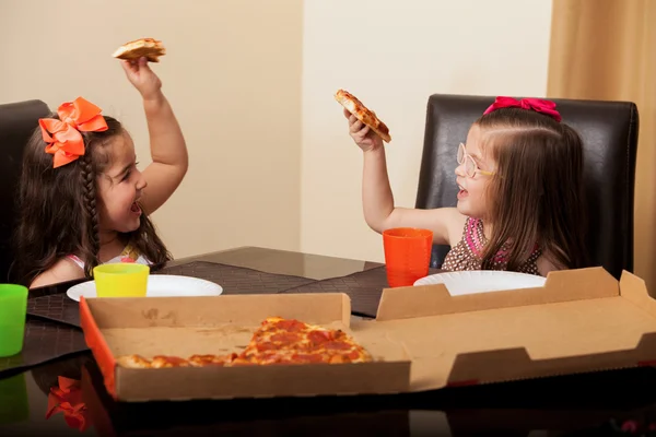 Pretty little cousins having fun and making a toast with pizza at home — Stock Photo, Image