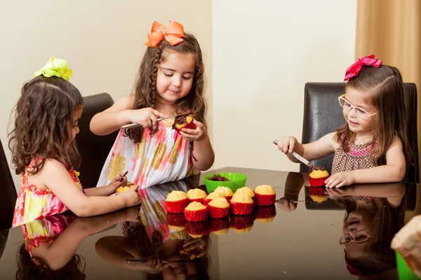 Meninas pequenas assar e decorar cupcakes — Fotografia de Stock