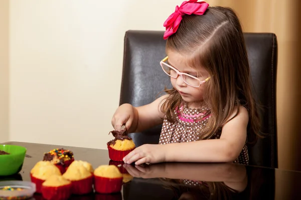 Beautiful little girl decorating cupcakes — Stock Photo, Image