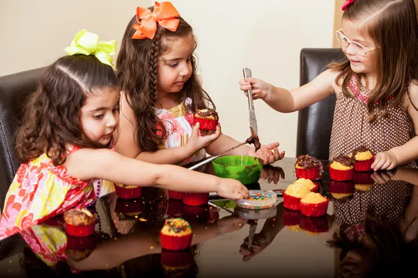 Meninas doces decorando alguns cupcakes juntos em casa — Fotografia de Stock