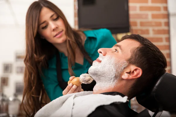 Female barber shaving a man — Stock Photo, Image