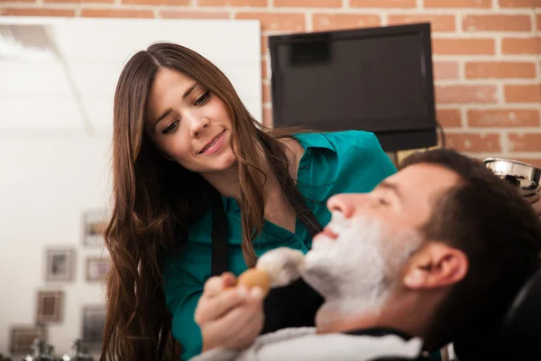 Счастливый парикмахер бреет клиента — стоковое фото