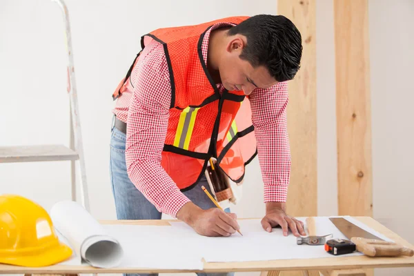 Contratante hispânico desenhando e modificando um modelo de uma casa — Fotografia de Stock