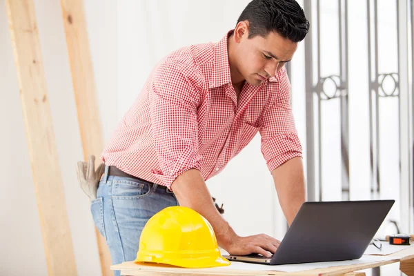 Engenheiro jovem atraente fazendo alguns trabalhos de construção e usando um laptop no local — Fotografia de Stock