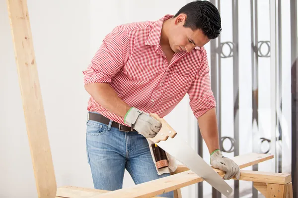 Jovem empreiteiro latino fazendo algum trabalho de carpintaria em uma casa — Fotografia de Stock