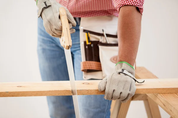 Primo piano di un falegname con una sega a mano per tagliare alcune tavole di legno — Foto Stock