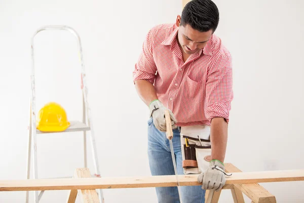 Fiatal férfi vállalkozó segítségével handsaw vágni néhány fa deszkák, egy ház átalakítás — Stock Fotó