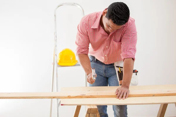 Jeune homme utilisant un marteau pour clouer des planches de bois en place — Photo