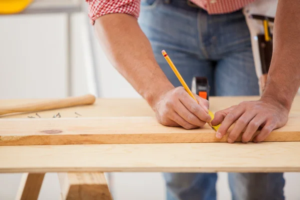 Close-up van een timmerman markering naar beneden bepaalde dimensies in een houten bord — Stockfoto