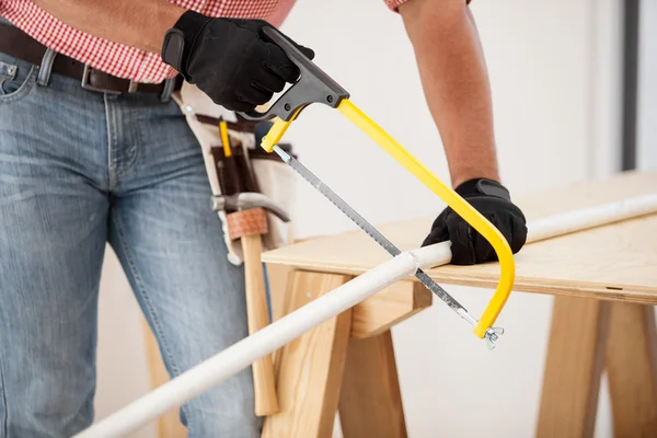 Closeup of a plumber using a hacksaw to cut down some pipes — Stock Photo, Image