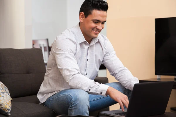 Portrait of a good-looking young man using a laptop computer to work from home home — Stock Photo, Image