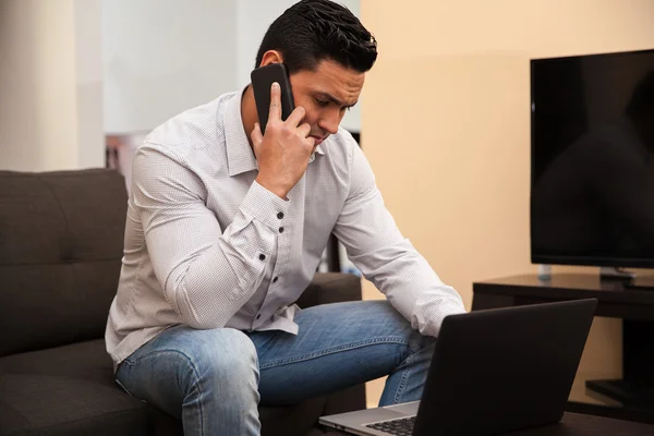 Drukke jonge man praten over de telefoon terwijl het werken vanuit huis — Stockfoto