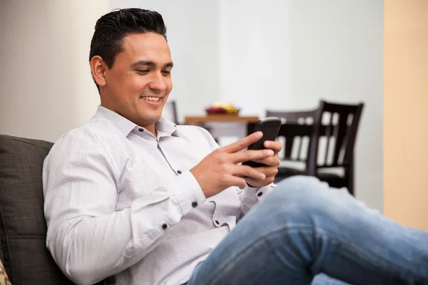 Jovem feliz redes sociais e mensagens de texto com seu telefone inteligente em casa — Fotografia de Stock