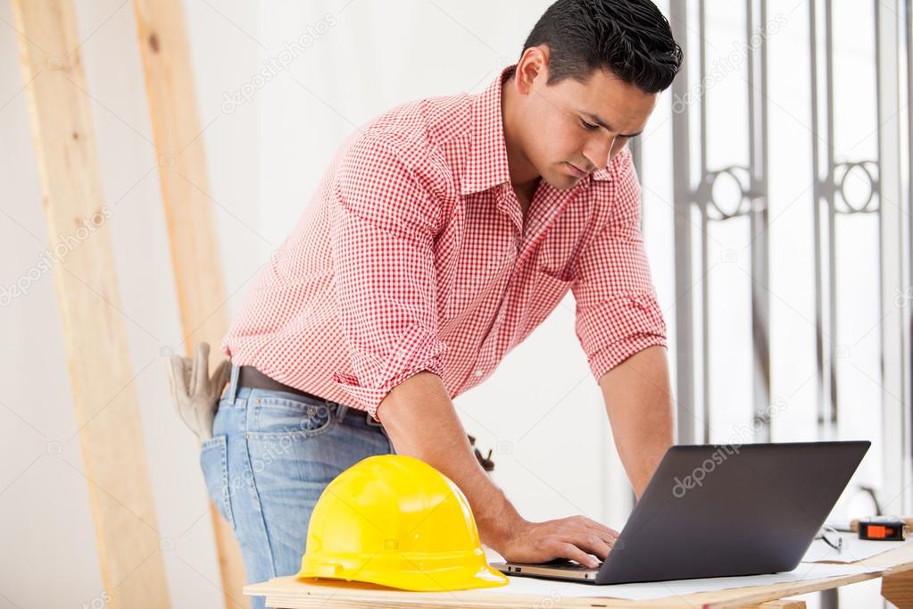 Attractive young engineer doing some construction work and using a laptop on site