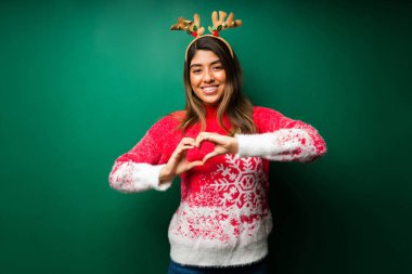 Noel 'i seviyorum. Çekici kadın elleriyle kalp hareketi yapıyor. 