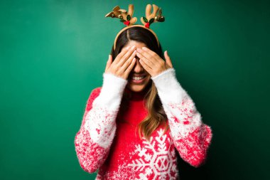 Neşeli genç bir kadın gözlerini kapatıyor ve sürpriz Noel hediyesini bekliyor. 