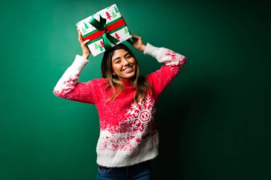 Hediyelerimizi vermeye hazırız. Çekici bir kadının portresi Noel hediyesini kafasının üstünde tutuyor ve eğleniyor.