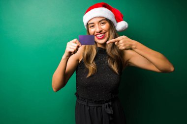 Kredi kartıyla ödeme. Kredi kartını gösteren ve işaret eden mutlu güzel bir kadının portresi. 